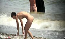 काले बालों वाली नंगी लड़की समुद्र तट पर नंगी घूमती हुई।